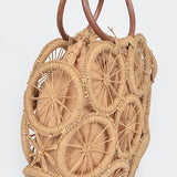 Natural raffia woven circle handbag with wooden ring handles and sunburst pattern—neutral beach tote