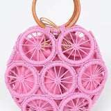 Bright pink woven circle tote bag with wooden ring handles and raffia sunburst design—boho summer handbag.