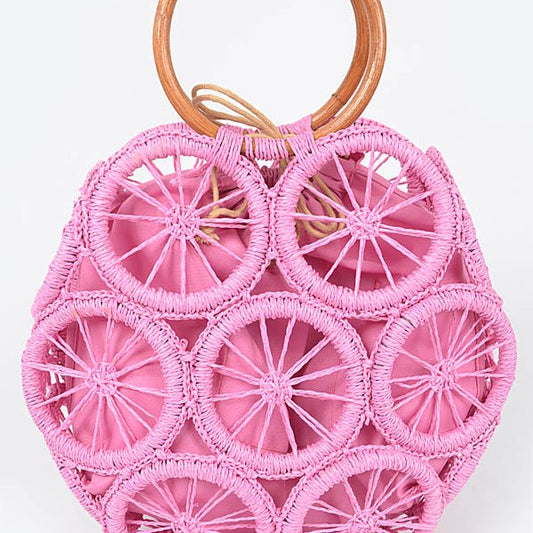 Bright pink woven circle tote bag with wooden ring handles and raffia sunburst design—boho summer handbag.