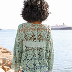 Close-up of mint green floral crochet wrap tied at the front, worn over a white crop top.