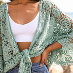 Close-up of mint green floral crochet wrap tied at the front, worn over a white crop top.