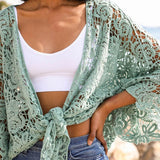 Close-up of mint green floral crochet wrap tied at the front, worn over a white crop top.