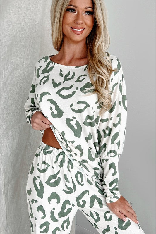 Woman standing and smiling in full-length view of sage and white animal print loungewear set, styled with sneakers and a mini handbag.