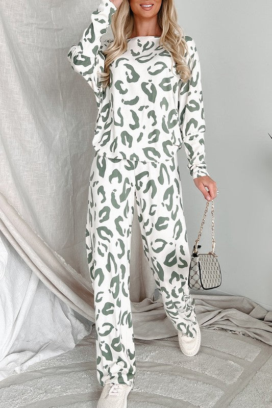 Woman standing and smiling in full-length view of sage and white animal print loungewear set, styled with sneakers and a mini handbag.