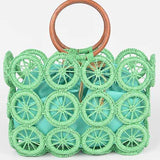 Mint green raffia circle-grid tote with wooden round handles and teal drawstring insert.