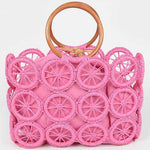 Bright pink woven circle-grid raffia tote with wooden ring handles and removable drawstring pouch.