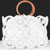 White raffia circle-grid handbag with contrasting wooden handles and secure drawstring pouch.