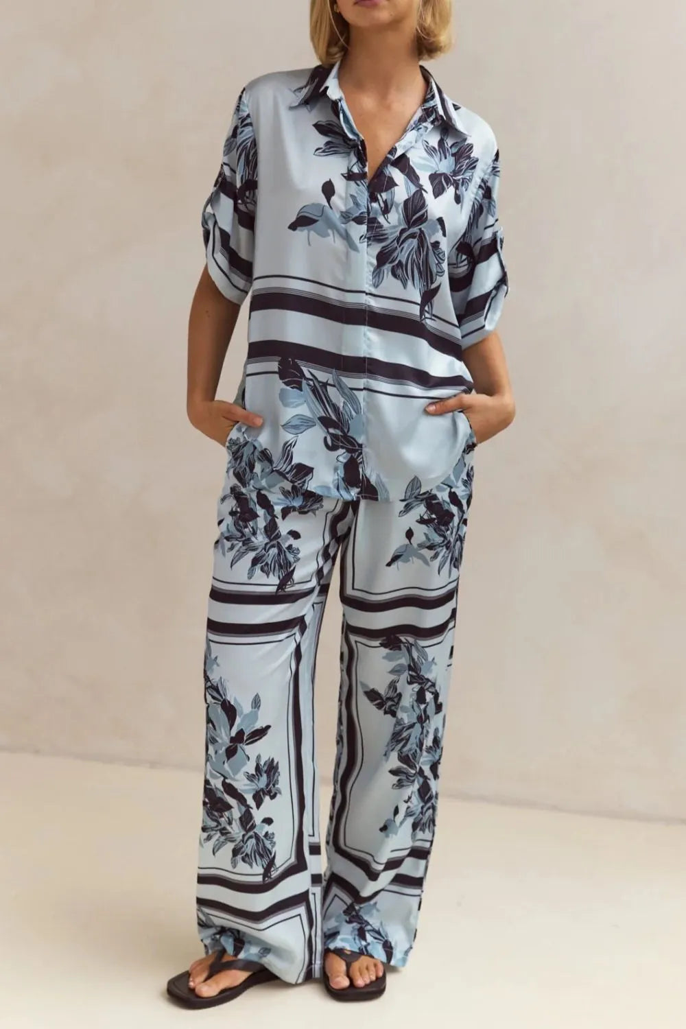 Light blue floral two-piece lounge set for women with short-sleeve button-down shirt and drawstring wide-leg pants, featuring navy botanical print – perfect for vacation, resort wear, or chic loungewear looks.