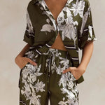 Olive green floral lounge set for women featuring short-sleeve button-down top and wide-leg pants with white botanical print – perfect for casual chic or resort wear.