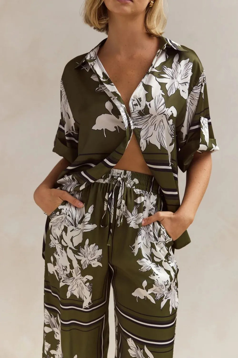 Olive green floral lounge set for women featuring short-sleeve button-down top and wide-leg pants with white botanical print – perfect for casual chic or resort wear.