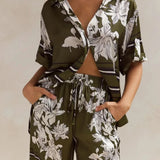 Olive green floral lounge set for women featuring short-sleeve button-down top and wide-leg pants with white botanical print – perfect for casual chic or resort wear.