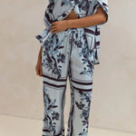 Light blue floral two-piece lounge set for women with short-sleeve button-down shirt and drawstring wide-leg pants, featuring navy botanical print – perfect for vacation, resort wear, or chic loungewear looks.