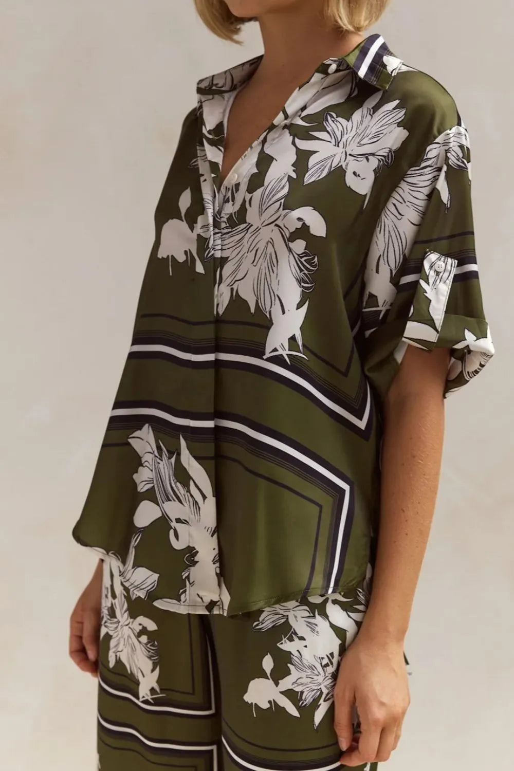 Olive green floral lounge set for women featuring short-sleeve button-down top and wide-leg pants with white botanical print – perfect for casual chic or resort wear.