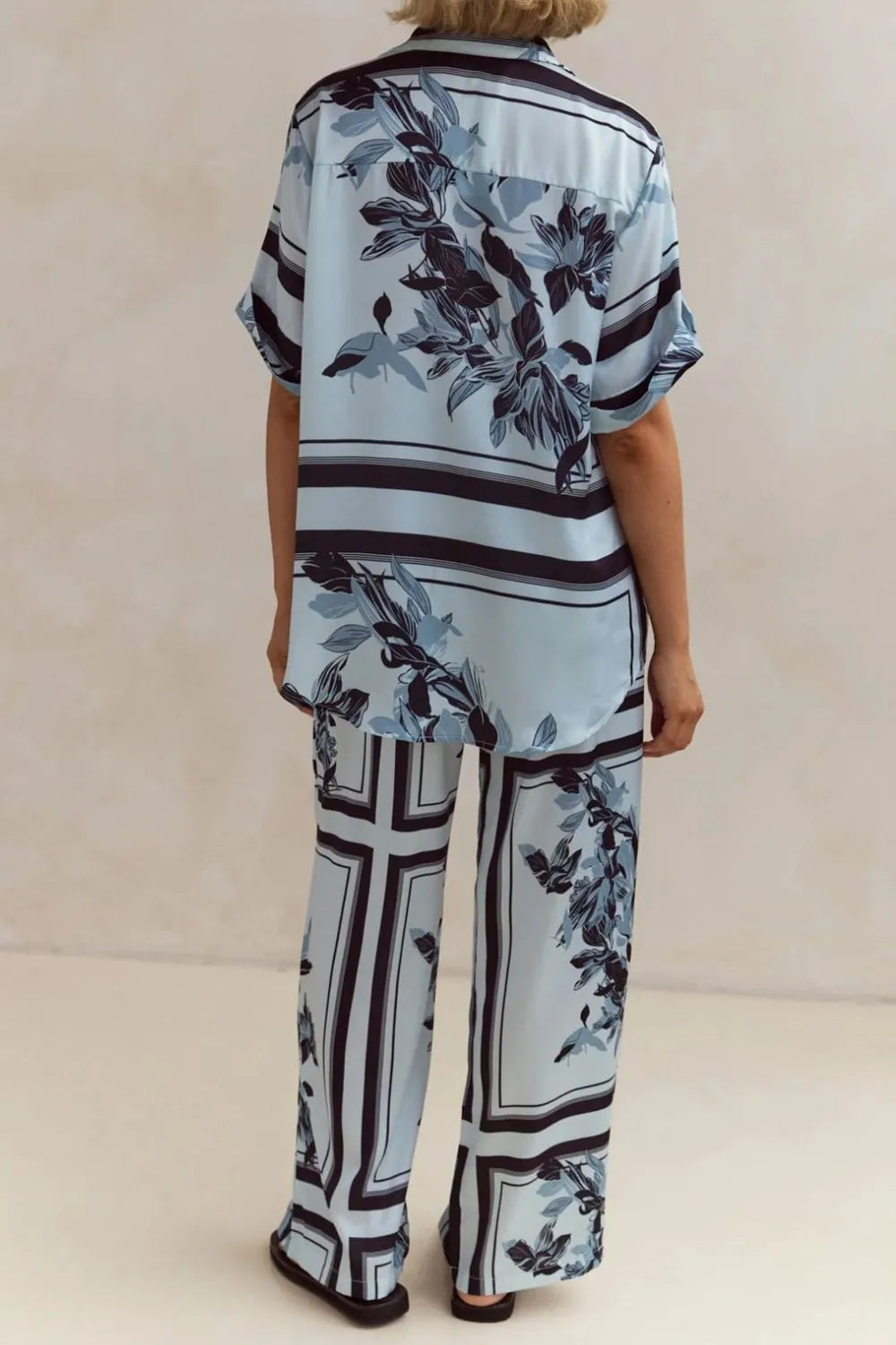 Light blue floral two-piece lounge set for women with short-sleeve button-down shirt and drawstring wide-leg pants, featuring navy botanical print – perfect for vacation, resort wear, or chic loungewear looks.