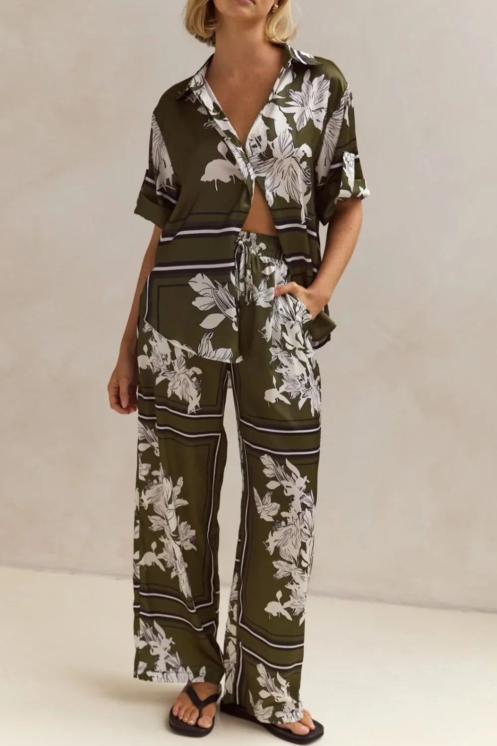 Olive green floral lounge set for women featuring short-sleeve button-down top and wide-leg pants with white botanical print – perfect for casual chic or resort wear.