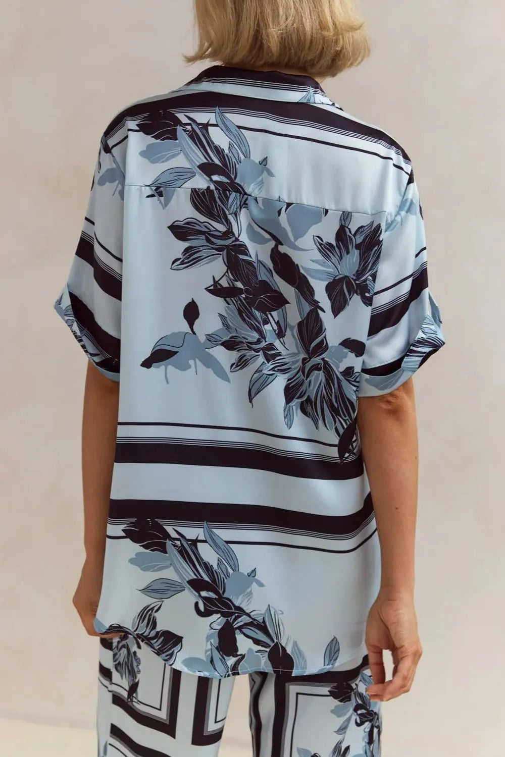 Light blue floral two-piece lounge set for women with short-sleeve button-down shirt and drawstring wide-leg pants, featuring navy botanical print – perfect for vacation, resort wear, or chic loungewear looks.