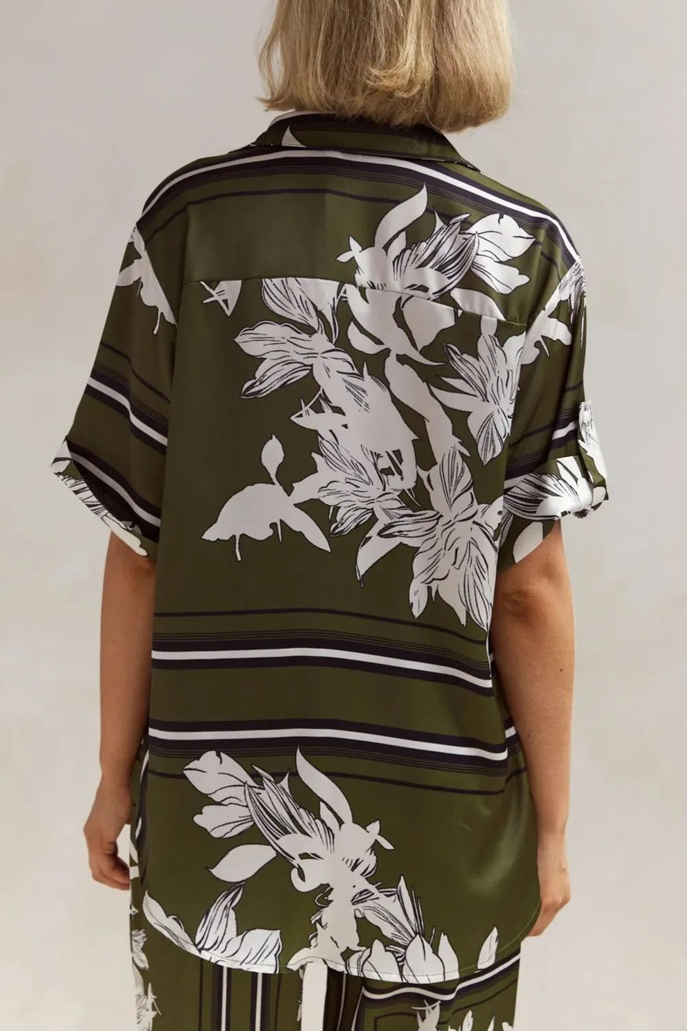 Olive green floral lounge set for women featuring short-sleeve button-down top and wide-leg pants with white botanical print – perfect for casual chic or resort wear.