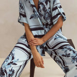 Light blue floral two-piece lounge set for women with short-sleeve button-down shirt and drawstring wide-leg pants, featuring navy botanical print – perfect for vacation, resort wear, or chic loungewear looks.