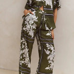 Olive green floral lounge set for women featuring short-sleeve button-down top and wide-leg pants with white botanical print – perfect for casual chic or resort wear.