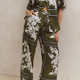 Olive green floral lounge set for women featuring short-sleeve button-down top and wide-leg pants with white botanical print – perfect for casual chic or resort wear.
