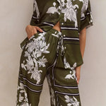 Olive green floral lounge set for women featuring short-sleeve button-down top and wide-leg pants with white botanical print – perfect for casual chic or resort wear.