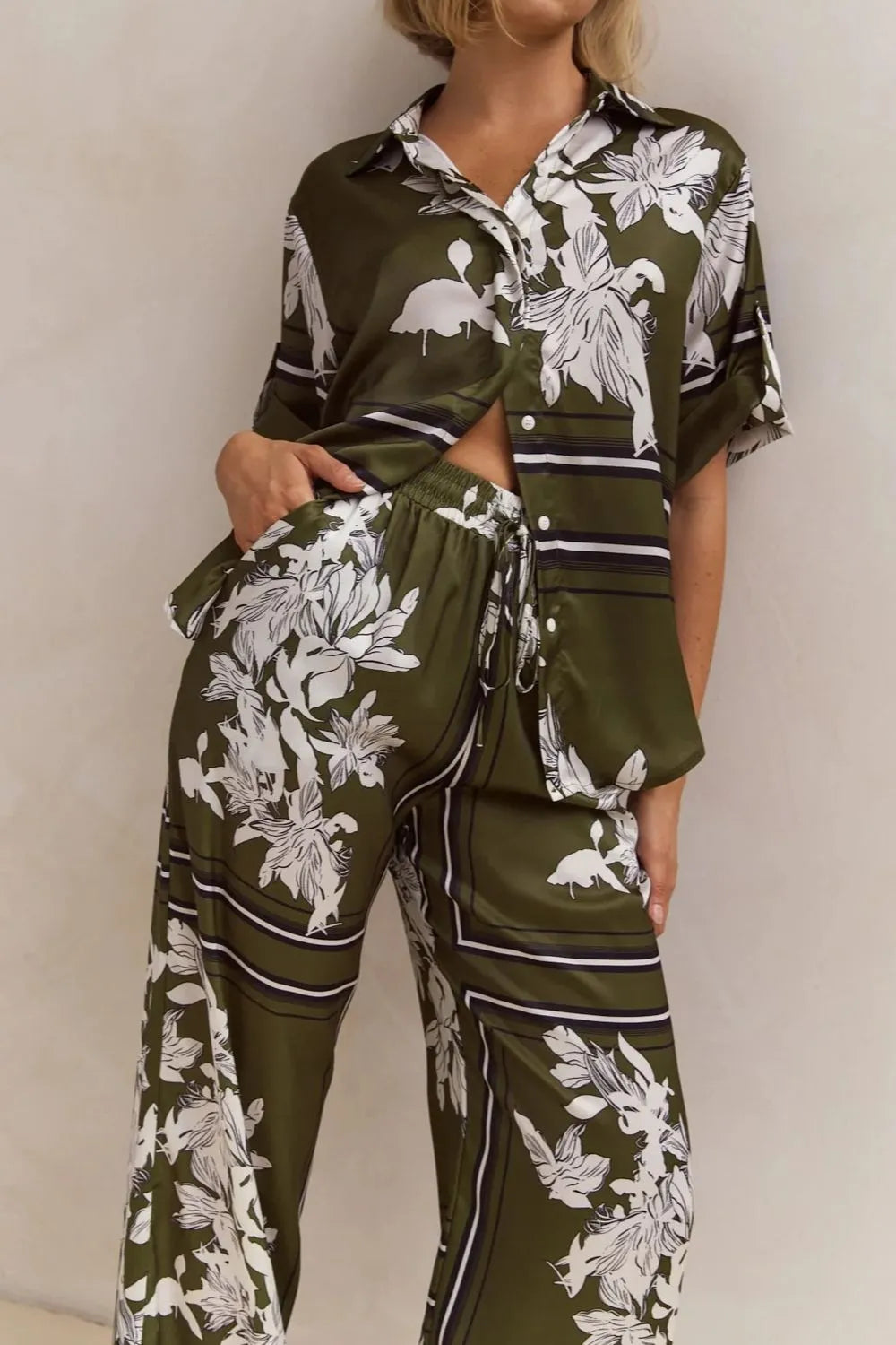 Olive green floral lounge set for women featuring short-sleeve button-down top and wide-leg pants with white botanical print – perfect for casual chic or resort wear.