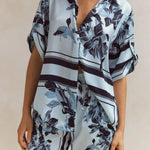Light blue floral two-piece lounge set for women with short-sleeve button-down shirt and drawstring wide-leg pants, featuring navy botanical print – perfect for vacation, resort wear, or chic loungewear looks.