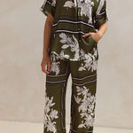 Olive green floral lounge set for women featuring short-sleeve button-down top and wide-leg pants with white botanical print – perfect for casual chic or resort wear.