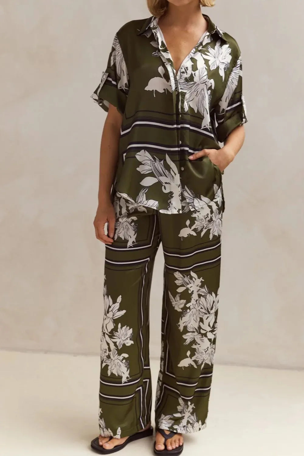 Olive green floral lounge set for women featuring short-sleeve button-down top and wide-leg pants with white botanical print – perfect for casual chic or resort wear.