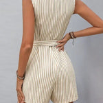 Woman wearing a beige and white vertical striped sleeveless romper with button front and waist tie, styled with hoop earrings and woven bag.