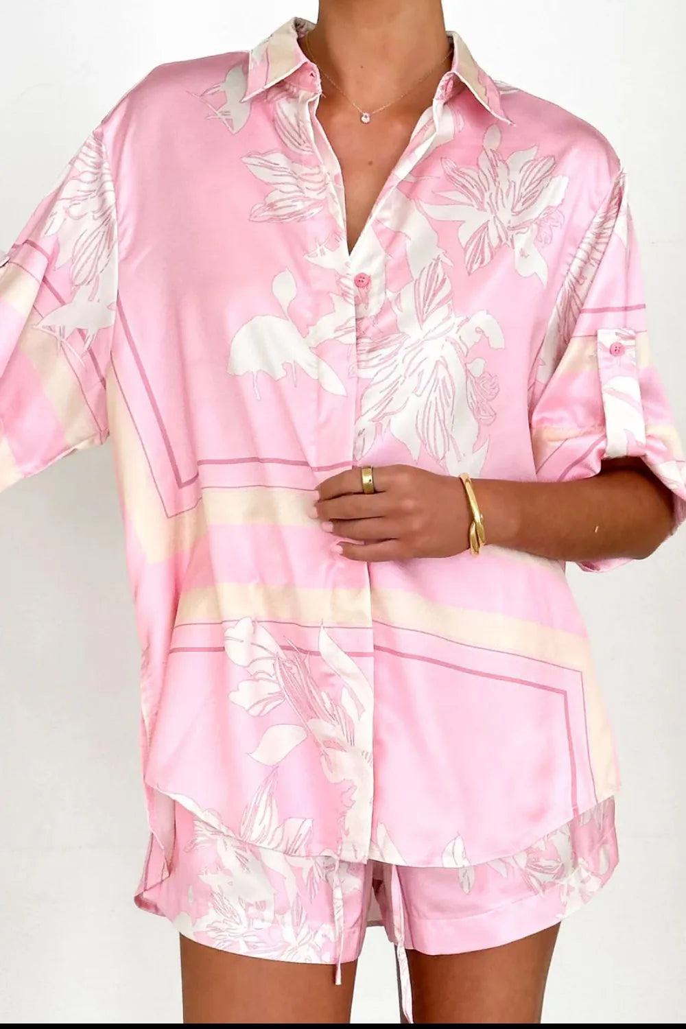 Women's blush pink tropical lily stripe two-piece outfit with loose button shirt and comfy drawstring shorts for resort wear.
