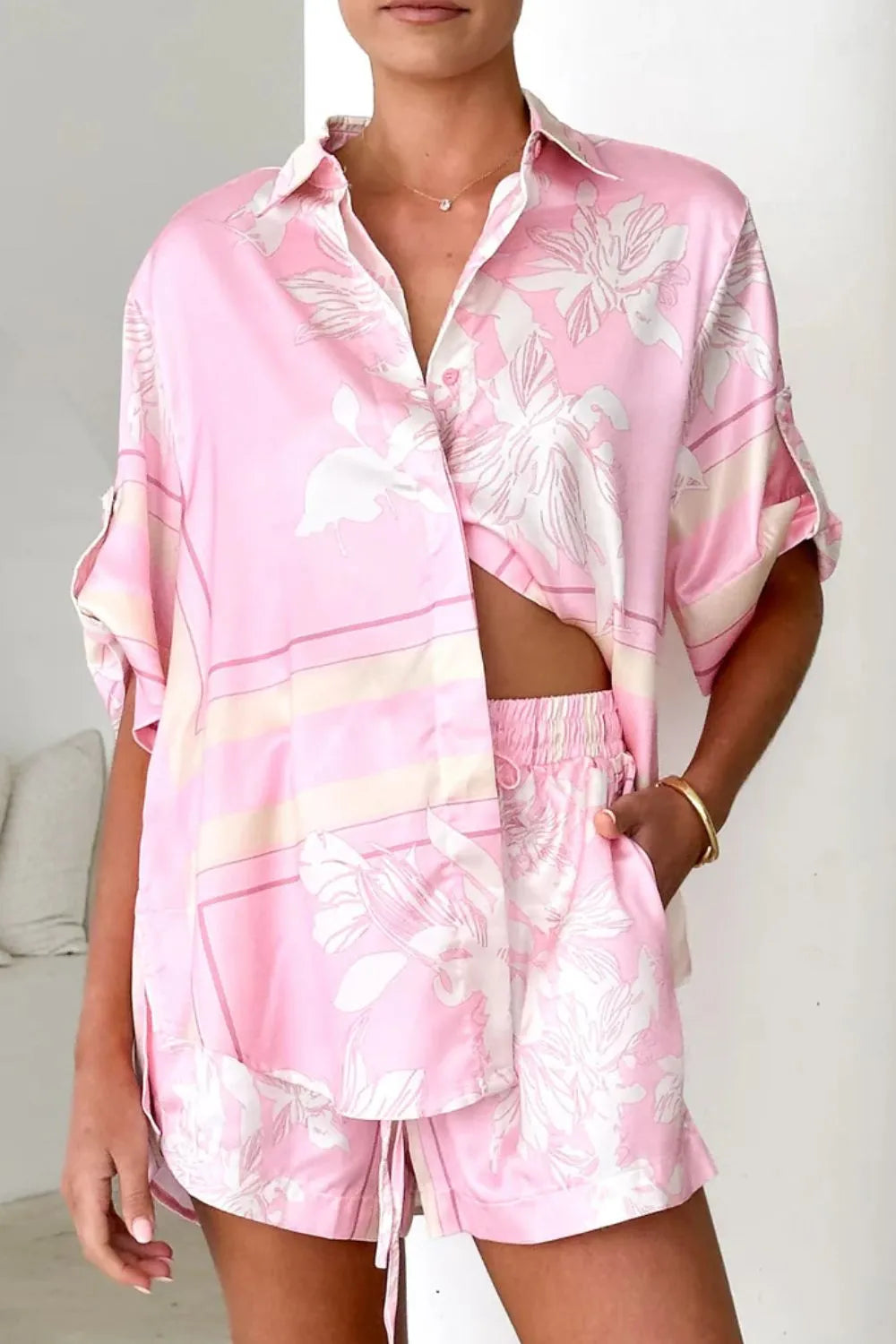 Women's blush pink tropical lily stripe two-piece outfit with loose button shirt and comfy drawstring shorts for resort wear.