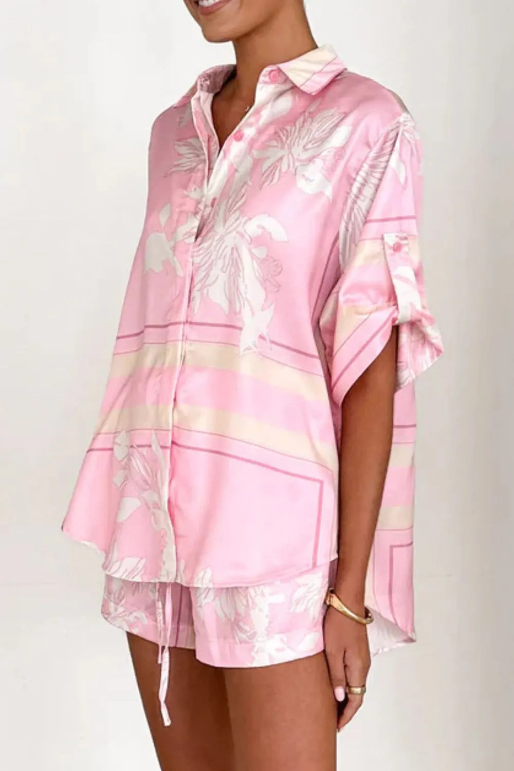 Women's blush pink tropical lily stripe two-piece outfit with loose button shirt and comfy drawstring shorts for resort wear.