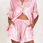 Women's blush pink tropical lily stripe two-piece outfit with loose button shirt and comfy drawstring shorts for resort wear.