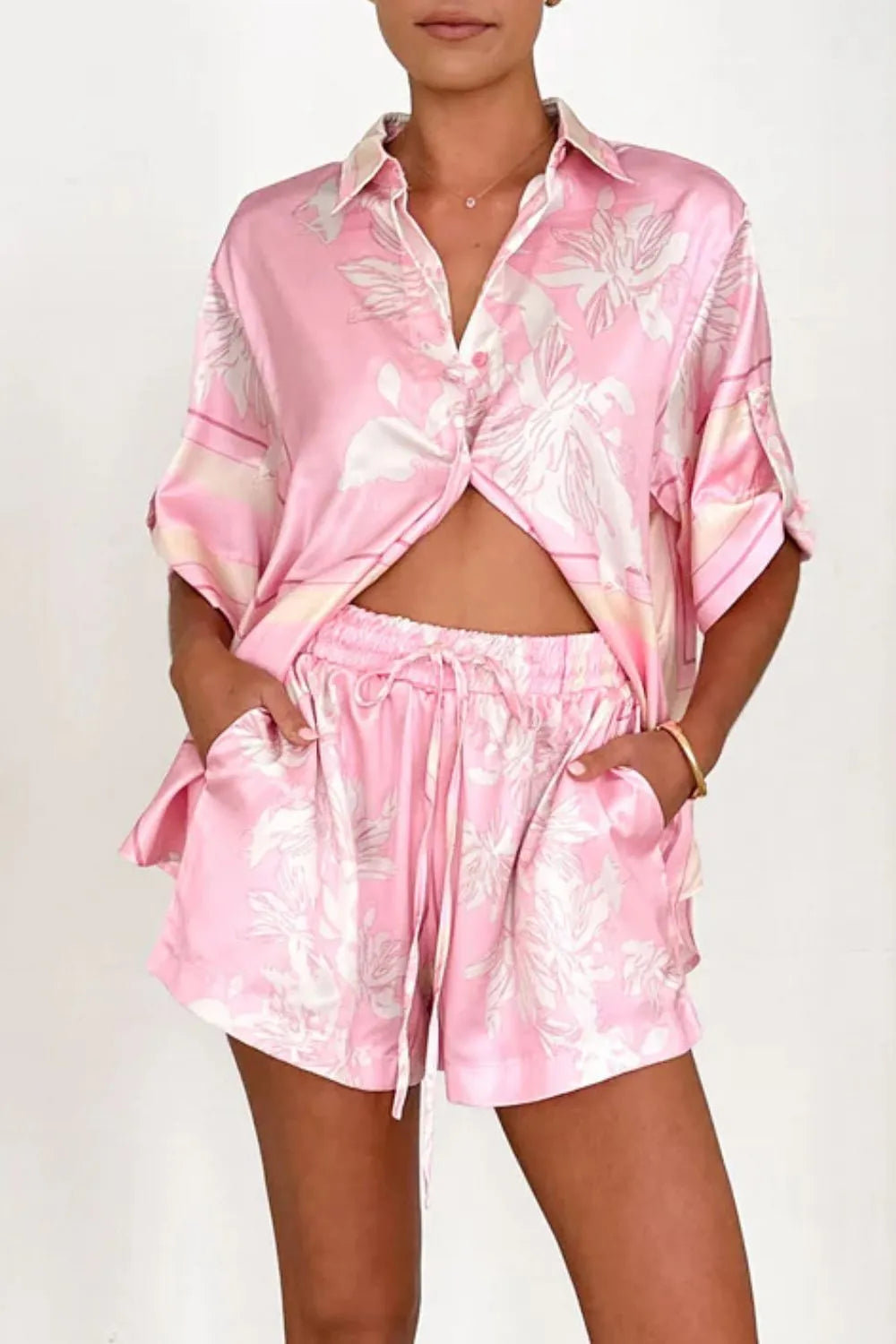 Women's blush pink tropical lily stripe two-piece outfit with loose button shirt and comfy drawstring shorts for resort wear.