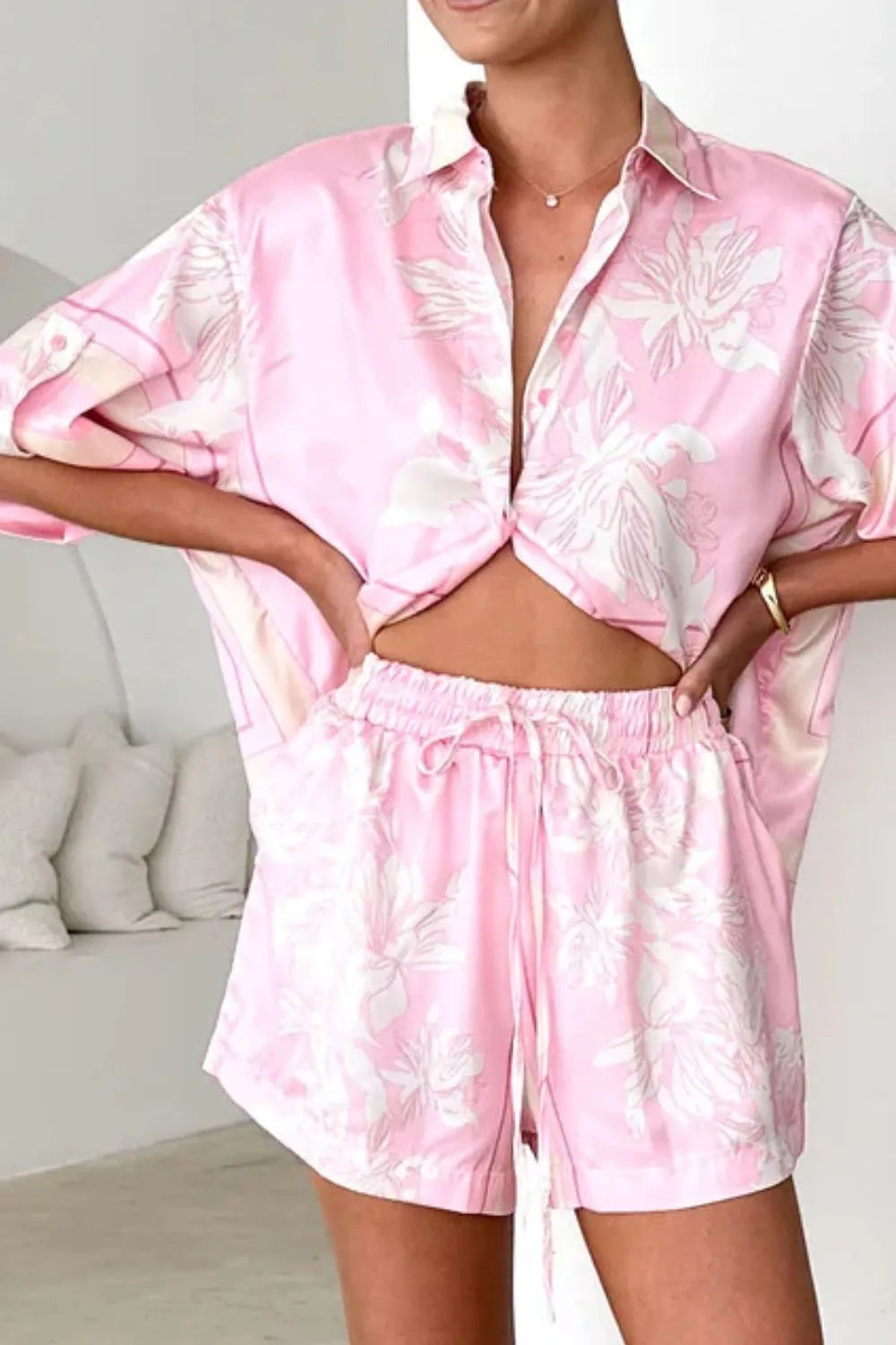 Women's blush pink tropical lily stripe two-piece outfit with loose button shirt and comfy drawstring shorts for resort wear.