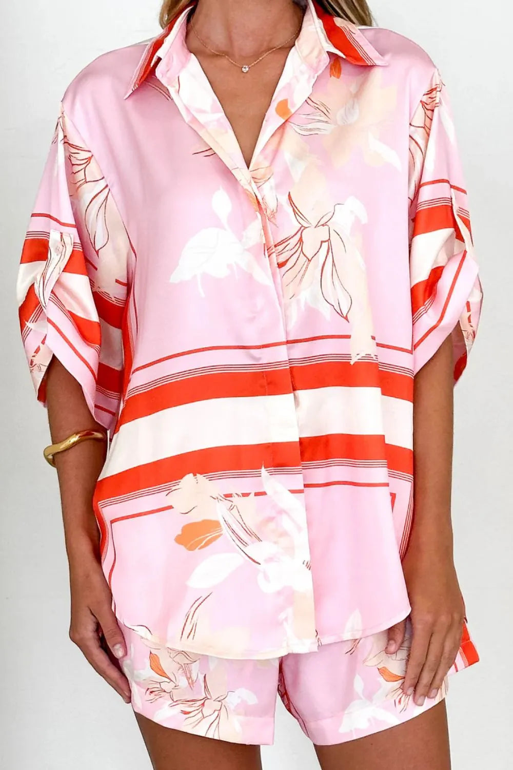 Women's blush pink tropical lily stripe two-piece outfit with loose button shirt and comfy drawstring shorts for resort wear.