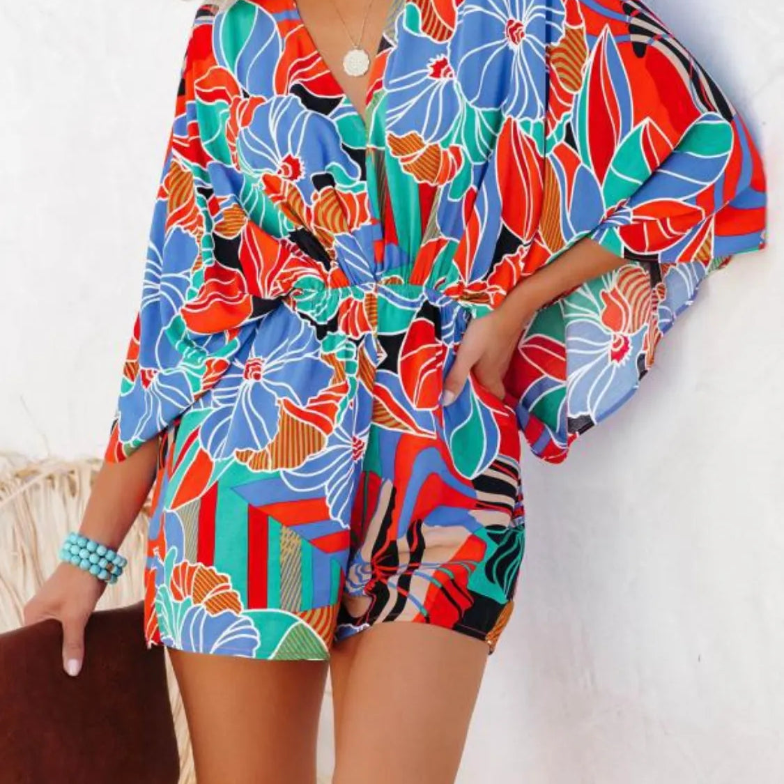 Women's multicolor tropical floral and geometric kimono-sleeve romper featuring surplice V-neck, cinched waist, and relaxed shorts—ideal for vacation wear.