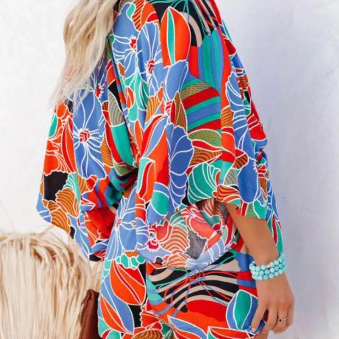 Women's multicolor tropical floral and geometric kimono-sleeve romper featuring surplice V-neck, cinched waist, and relaxed shorts—ideal for vacation wear.