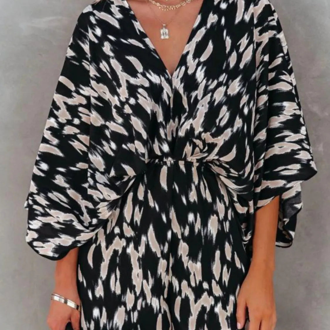 Women's black and taupe abstract animal-print kimono-sleeve romper with deep V-neck, cinched elastic waist, and flowy shorts.