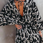 Women's black and taupe abstract animal-print kimono-sleeve romper with deep V-neck, cinched elastic waist, and flowy shorts.