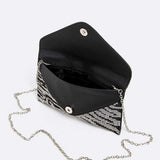 Open black and silver zebra print rhinestone clutch with silver chain strap and magnetic button closure.
