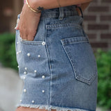 Women's high-waisted denim shorts with faux pearl embellishments and frayed hem – trendy summer jean shorts for casual and chic outfits.