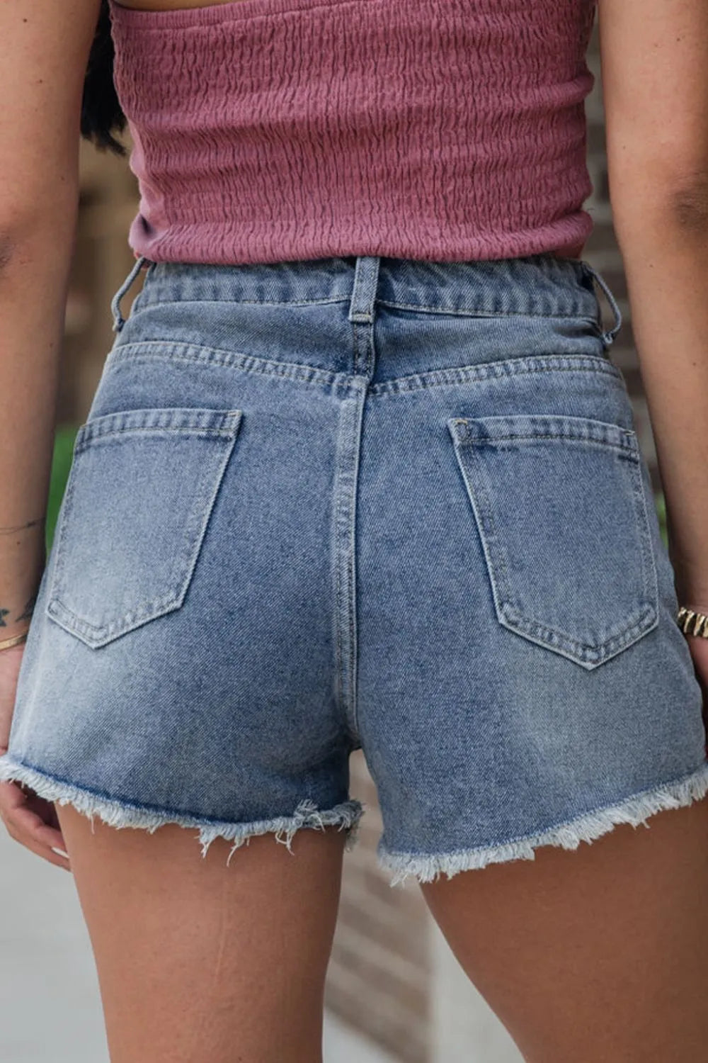 Women's high-waisted denim shorts with faux pearl embellishments and frayed hem – trendy summer jean shorts for casual and chic outfits.