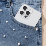 Women's high-waisted denim shorts with faux pearl embellishments and frayed hem – trendy summer jean shorts for casual and chic outfits.