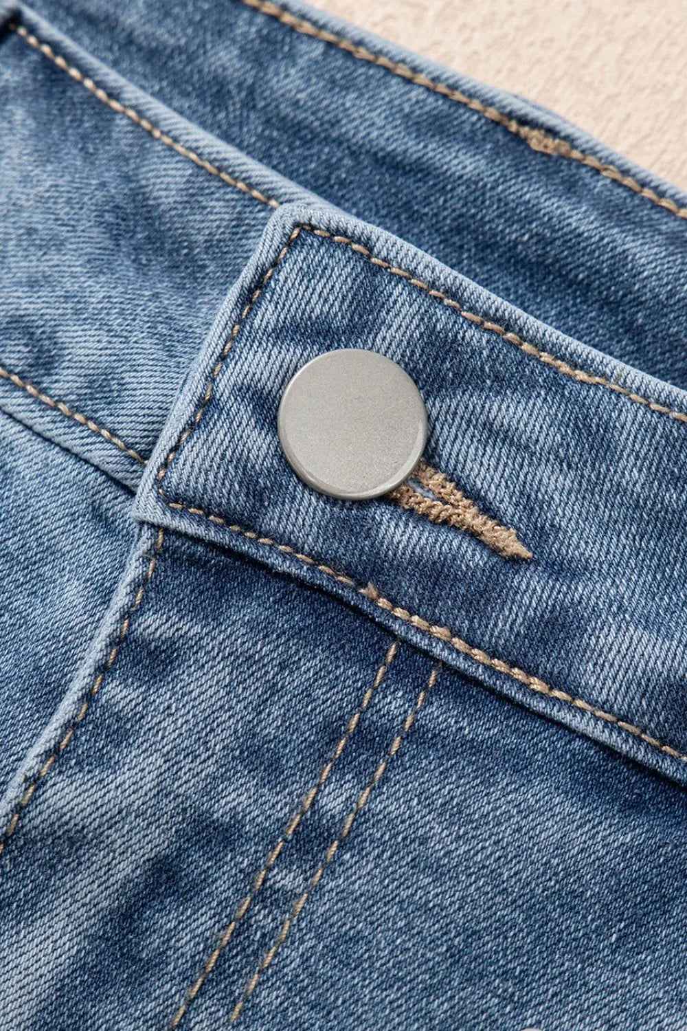 Women's high-waisted denim shorts with faux pearl embellishments and frayed hem – trendy summer jean shorts for casual and chic outfits. Showing the detail.