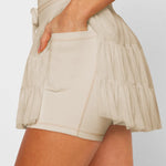 Women's sand beige ruffle tennis skort with high-waist fit, adjustable drawstring, and built-in stretch shorts for workouts.