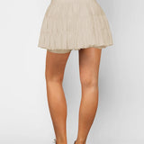 Women's sand beige ruffle tennis skort with high-waist fit, adjustable drawstring, and built-in stretch shorts for workouts.