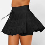 Women's black high-waist ruffle athletic skort with triple mesh tiers, drawstring waistband, and hidden shorts.