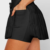 Women's black high-waist ruffle athletic skort with triple mesh tiers, drawstring waistband, and hidden shorts.